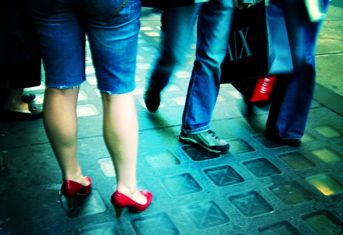 person in red heels standing on sidewalk