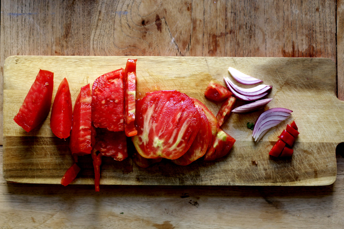 chopped tomatoes and red onions on a wooden cutting board