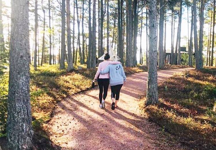 two white women walking through the woods with their arms around each other