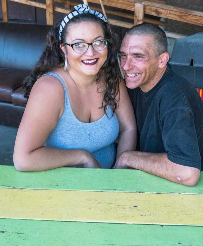 a woman and a man sitting next to each other on a bench, smiling