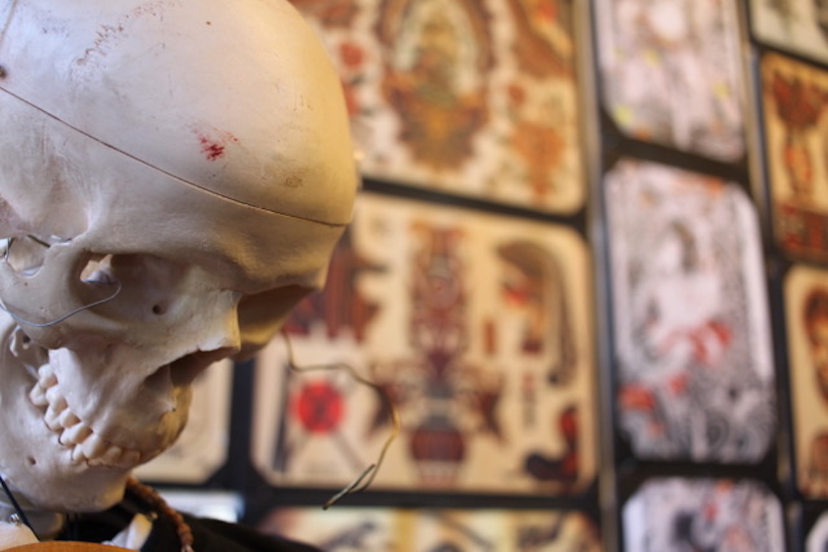 a skull set in front of a wall of tattoo flash