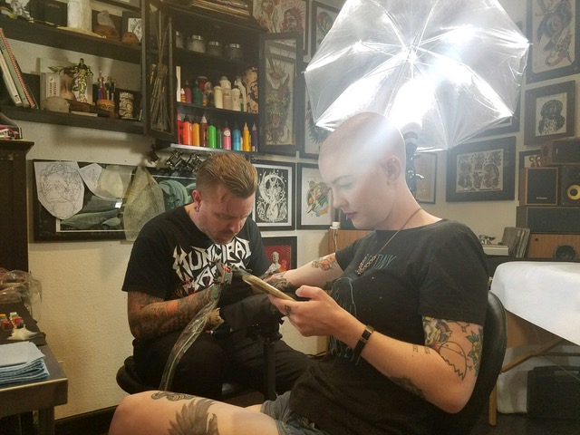 The author getting tattooed while looking at her phone